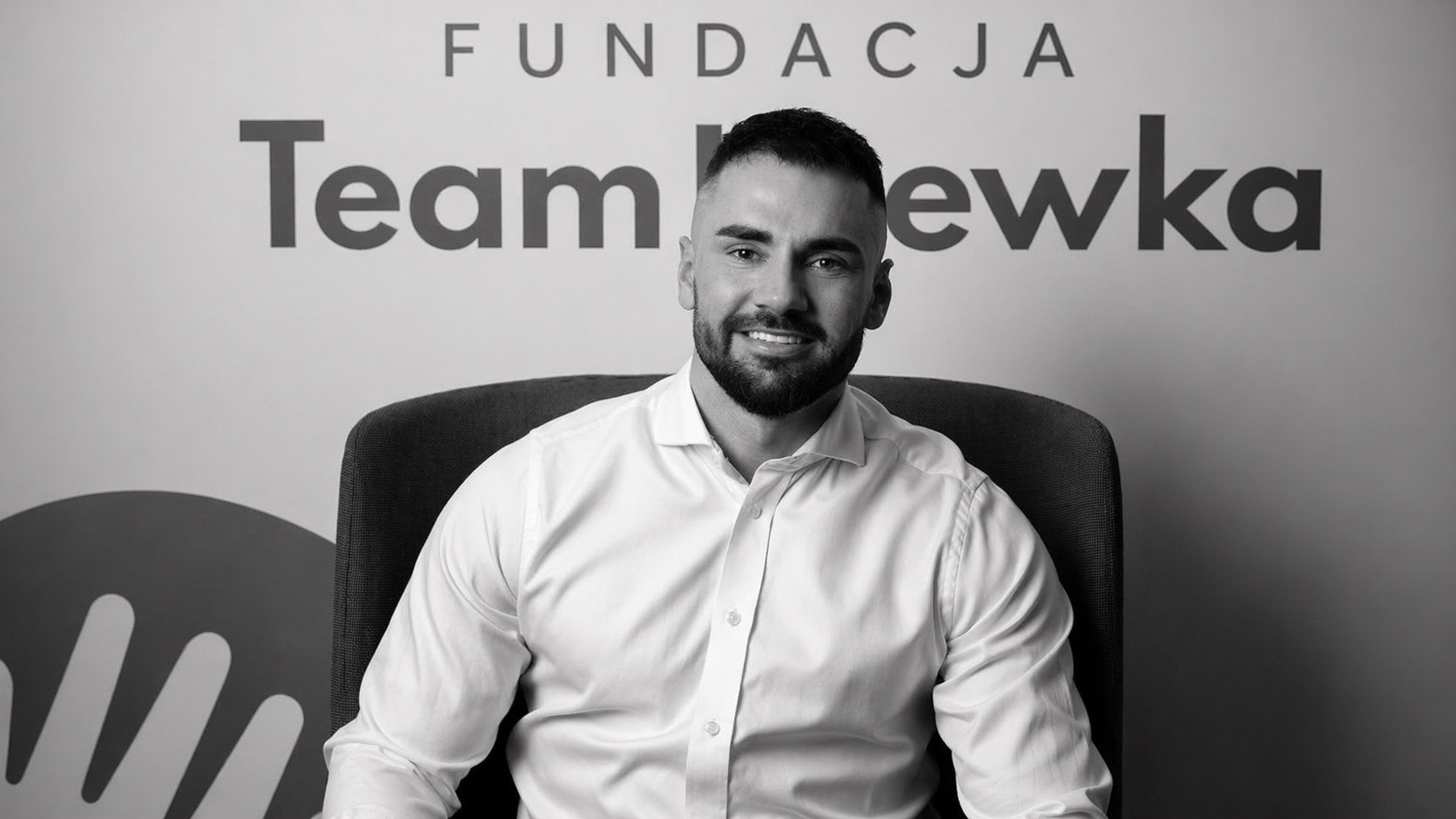 Łukasz Litewka na tle napisu Fundacja Team Litewka – czarno-białe zdjęcie